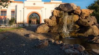 Image of the front of the Bureau of Mining and a pond and waterfall in the foreground